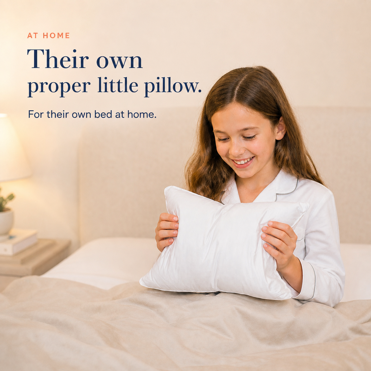 Child holding a Goose Down Mini Children’s Pillow on her bed at home